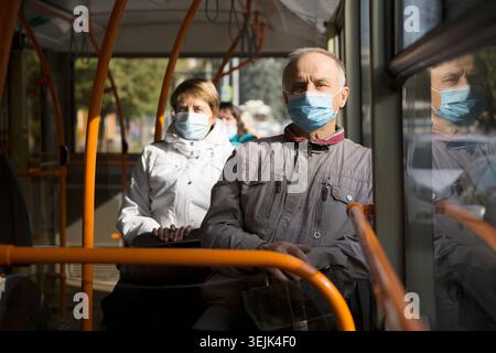 Homme senior portant un masque médical assis dans le transport en bus. Banque D'Images