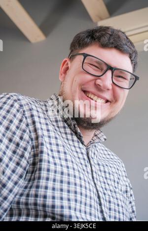 Homme assis sur le lit regardant la caméra et souriant Banque D'Images