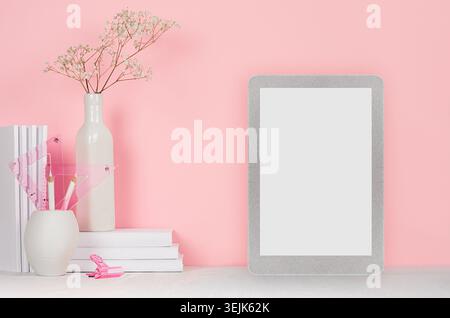 Lieu de travail de mode moderne - tablette tactile argentée avec écran blanc, papeterie blanche sur fond rose doux. Banque D'Images