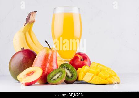 Boisson fraîche d'été de fruits tropicaux avec mangue mûre tranchée, kiwi et banane sur la table en bois blanc, gros plan. Banque D'Images