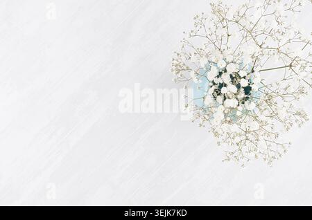 Fond frais d'été avec des fleurs aérées dans un vase bleu sur planche de bois blanc vue de dessus avec espace de copie. Banque D'Images