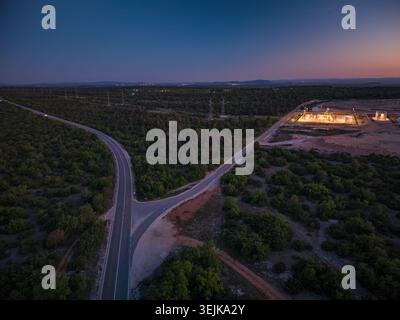 Vue aérienne de la sous-station éclairée VP Korlat et d'un carrefour routier entouré d'une végétation dense au crépuscule Korlat, Zadarska zupanija, Croatie. Banque D'Images