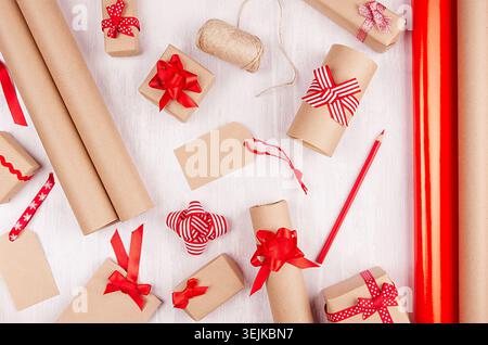 Fond de préparation de Noël - papier d'emballage, boîtes-cadeaux, ruban rouge et noeuds, ficelle comme motif festif sur bo en bois blanc Banque D'Images