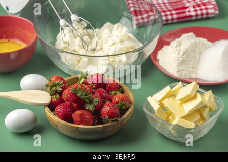 Ingrédients de boulangerie frais, y compris les fraises, le beurre, le sucre et le fromage blanc, sur fond vert Banque D'Images
