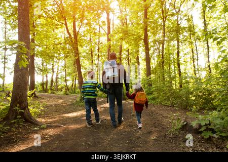 Père et deux enfants avec sac à dos randonnée dans la forêt. Distanciation sociale. Détox numérique. Staycations, voyage hyper-local, famille o Banque D'Images