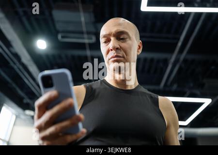 Fit homme à l'aide d'un smartphone dans la salle de gym après l'entraînement Banque D'Images