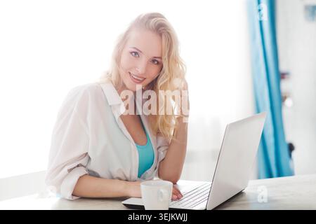 La femme enceinte travaille sur un ordinateur portable à la maison et boit du thé. bureau à domicile. Banque D'Images