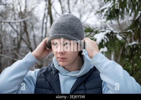Jeune homme marchant dans le parc et portant un chapeau d'hiver. Style de vie en extérieur Banque D'Images