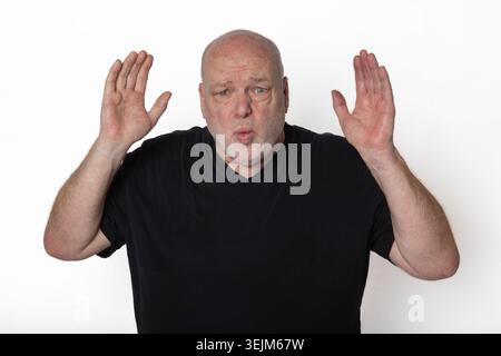 Homme senior surpris tenant les mains vers le haut isolé sur fond blanc. Banque D'Images