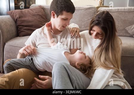 La famille s'amuse à passer du temps ensemble à la maison. maman, papa et deux fils enfants jouent, s'embrassent et s'amusent ensemble à la maison. Christm Banque D'Images