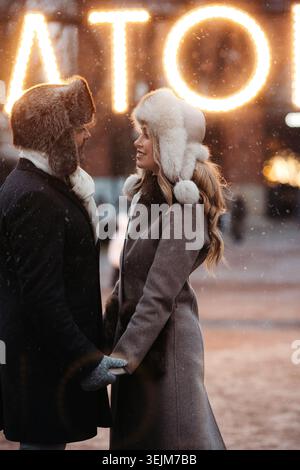 Un couple d'amoureux de la mode s'embrassant, debout sur la rue d'hiver par temps enneigé. Saint-Valentin Banque D'Images