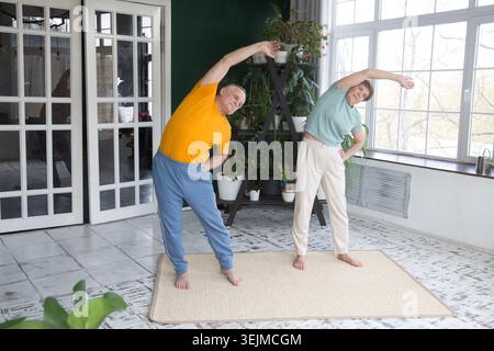 Couple de personnes âgées mode de vie sain. Couple senior faisant des exercices à la maison le matin. Banque D'Images