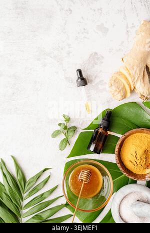 Ingrédients cosmétiques naturels sur la table. Poudre de curcuma, miel, gingembre et huile essentielle sur feuille de monstera Banque D'Images