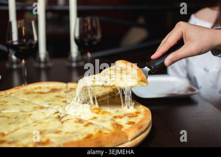 Gros plan des mains saisissant des tranches de pizza chaude, étirant le fromage Banque D'Images