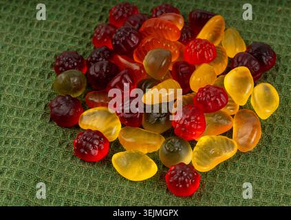 Pile de bonbons gélifiés aux fruits en gros plan, pilules de marmelade végétalienne à mâcher, tas de gumdrops de gelée, macro de bonbons en gélatine colorés sur fond vert Banque D'Images