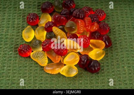 Pile de bonbons gélifiés aux fruits en gros plan, pilules de marmelade végétalienne à mâcher, tas de gumdrops de gelée, macro de bonbons en gélatine colorés sur fond vert Banque D'Images