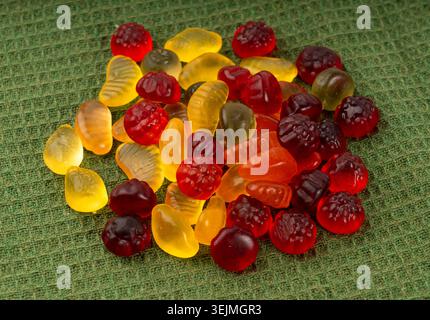 Pile de bonbons gélifiés aux fruits en gros plan, pilules de marmelade végétalienne à mâcher, tas de gumdrops de gelée, macro de bonbons en gélatine colorés sur fond vert Banque D'Images