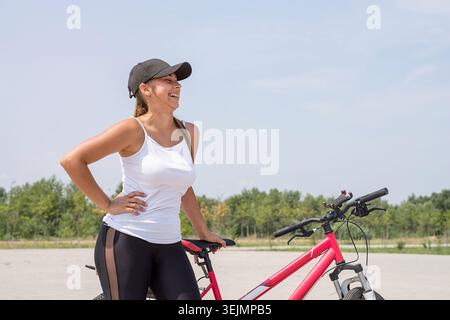 Femme insouciante faisant du vélo dans un parc et riant Banque D'Images