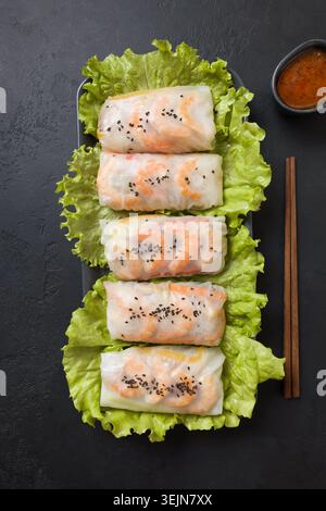 Rouleaux de printemps alimentaires vietnamiens avec des légumes, des crevettes dans du papier de riz sur noir. Vue de dessus. Cuisine asiatique. Banque D'Images