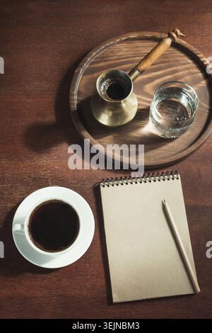 Tasse de café noir avec du cezve de cuivre et de l'eau de verre dans le style vintage. Vue de dessus. Banque D'Images