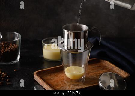 Verser de l'eau dans le filtre goutte-à-goutte pour cuire du café vietnamien avec du lait condensé sucré. Banque D'Images