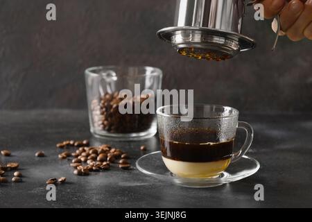 Infusez du café vietnamien avec du lait condensé sucré dans une tasse en verre. Banque D'Images