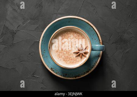 Masala thé indien ou café en tasse bleue avec épices et cannelle sur noir. Vue de dessus. Banque D'Images