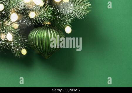 Boule rouge de Noël sur branche de sapin neigeux sur beige. Carte de Noël. Banque D'Images