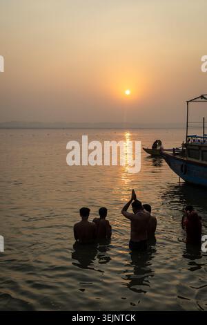 Une scène de lever de soleil calme au bord de la rivière avec prière de pèlerins et prise de vue en bateau de pêche en bois est prise à varanasi (banaras) uttar pradesh inde le 19 février 2025. Banque D'Images
