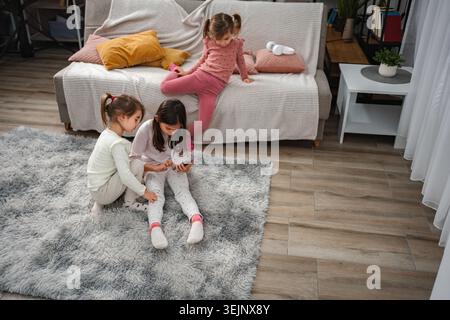 Filles jouant avec smartphone ensemble à la maison Banque D'Images