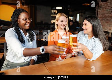Diverses femmes amies grillant la bière dans un bar Banque D'Images