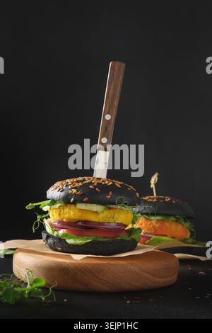 Vegan Burger de petits pains au charbon noir, boulettes de viande de légumes sur noir. Banque D'Images
