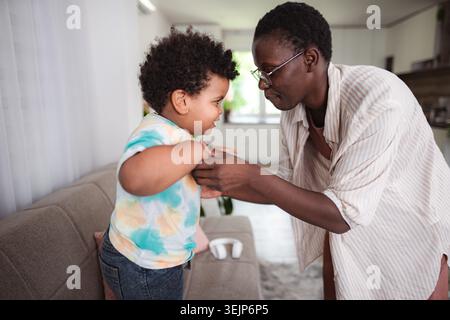 Mère aidant son fils à se lever à la maison Banque D'Images