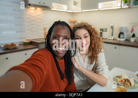 Diverses femmes amies souriantes prenant selfie dans la cuisine Banque D'Images