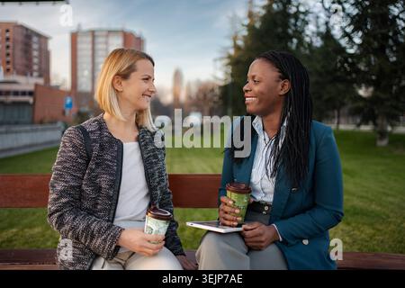 Diverses collègues femmes profitant d'une pause café dans le parc de la ville Banque D'Images