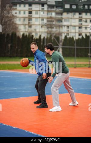 Hommes jouant au basket-ball en compétition sur un terrain extérieur Banque D'Images
