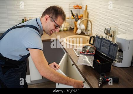 Homme mesurant armoire de cuisine pour réparation et rénovation Banque D'Images