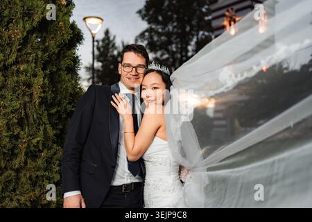 Couple diversifié souriant, célébrant un mariage multiculturel en plein air Banque D'Images