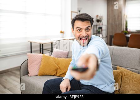 Homme assis sur le canapé tenant la télécommande Banque D'Images