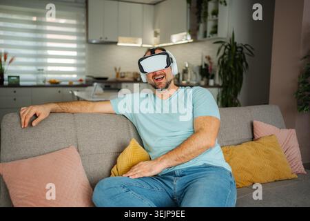 Homme expérimentant le jeu de réalité virtuelle portant casque VR à la maison Banque D'Images