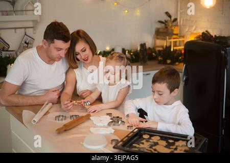 Heureux papa de famille, maman et deux enfants font des biscuits de Noël et amusez-vous ensemble à la maison dans la cuisine. Enfants frères et sœurs makin Banque D'Images
