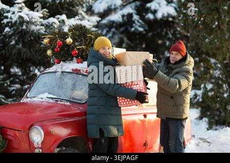 Retraités de couple senior en vêtements chauds d'hiver avec cadeau de Noël dans la rue. joyeux Noël ! Banque D'Images