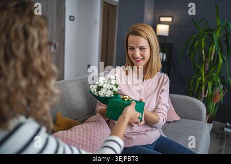 Femme assise sur le canapé tenant bouquet de fleurs Banque D'Images