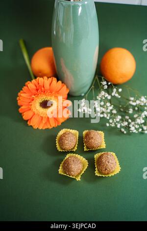 Boules énergétiques saines avec des oranges fraîches et des fleurs de gerbera vibrantes Banque D'Images