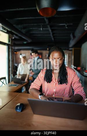 Femme d'affaires afro-américaine tapant ordinateur portable dans le bureau moderne Banque D'Images