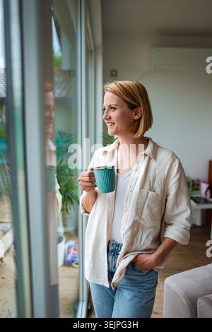 Femme profite d'un matin calme avec une boisson chaude Banque D'Images