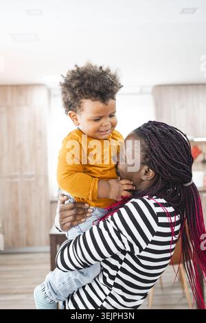 Famille multiraciale profitant de moments ludiques à l'intérieur avec un enfant en bas âge Banque D'Images
