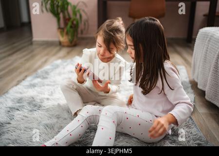 Filles partageant un smartphone, regardant ensemble du contenu éducatif Banque D'Images