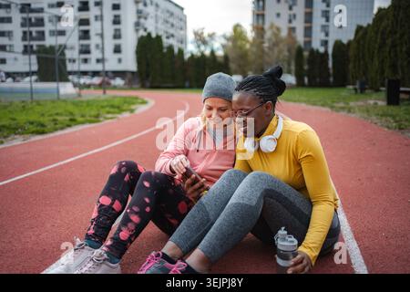 Diverses femmes amies se relaxant et regardant le téléphone après l'entraînement Banque D'Images