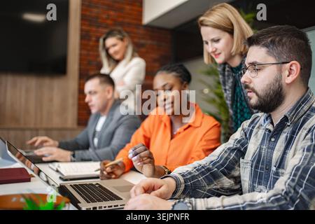Groupe de personnes assis à une table avec des ordinateurs portables Banque D'Images